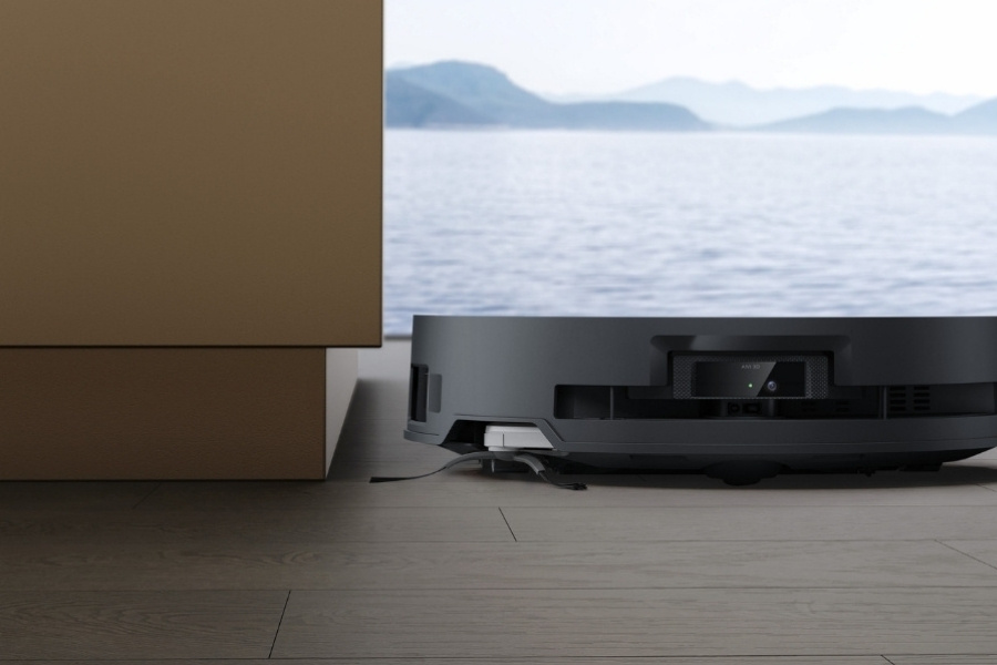 deebot robot vacuum picking up dust near cabinet