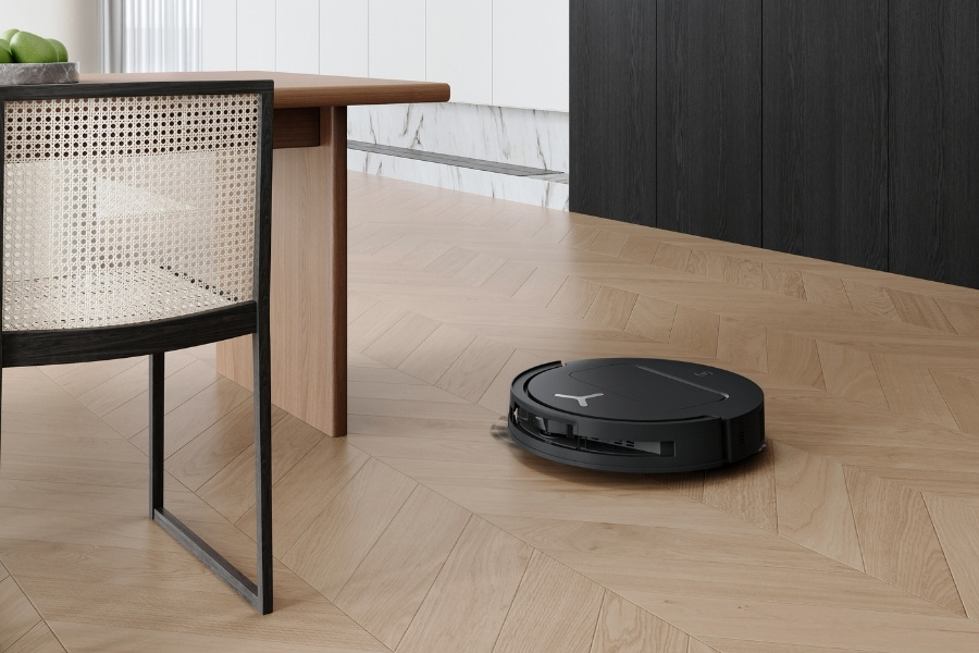 deebot robot vacuum cleaner vacuuming near a dining table