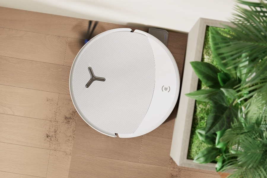deebot robot vacuum cleaning corner next to a plant pot
