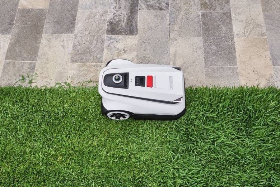 Ein GOAT Maehroboter der den Rand zwischen Gras und Fliesen schneidet