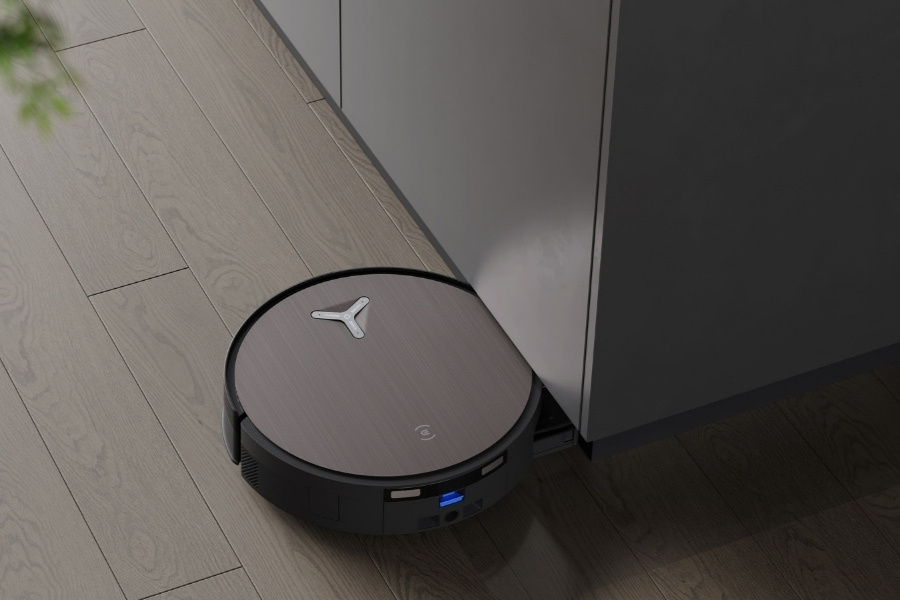 aspirateur robot DEEBOT nettoyant des epines de pin sous un meuble