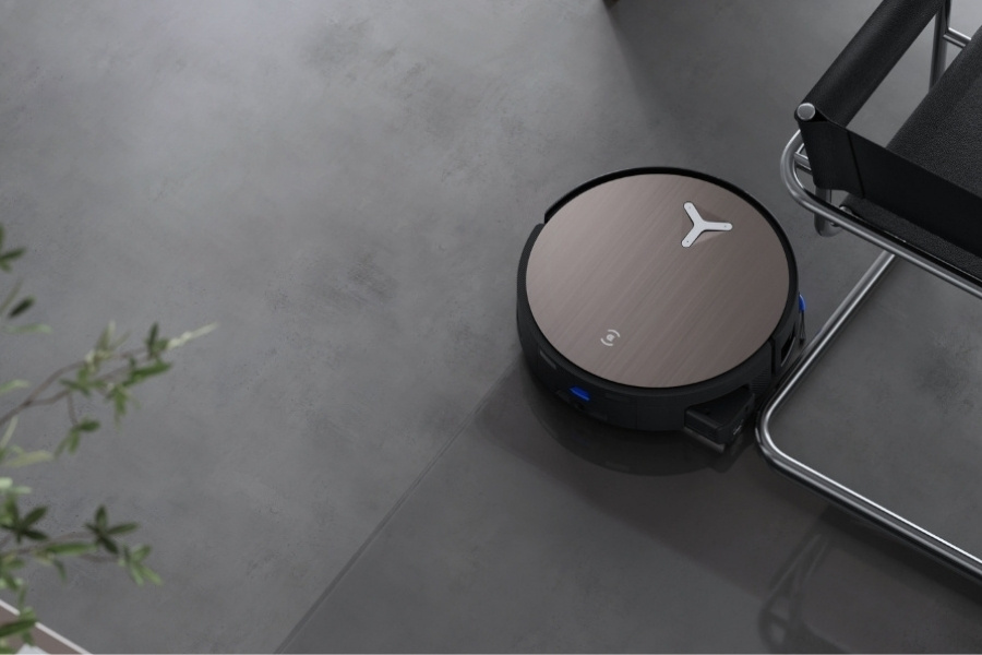 aspirateur robot deebot nettoyant un sol en beton pres d une chaise