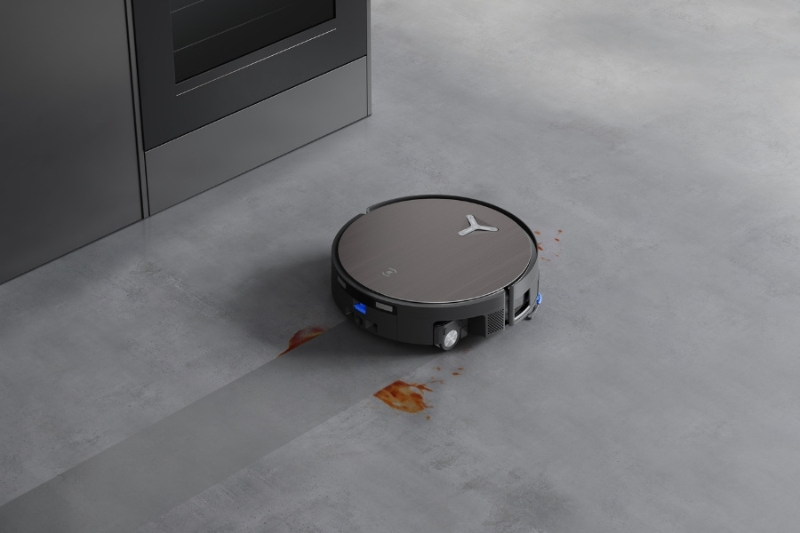 aspirateur robot DEEBOT nettoyant une tache de sauce tomate sur du beton