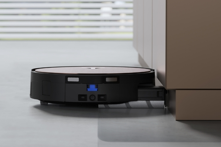 robot aspirateur deebot nettoyant le long du meuble sur un sol en pierre