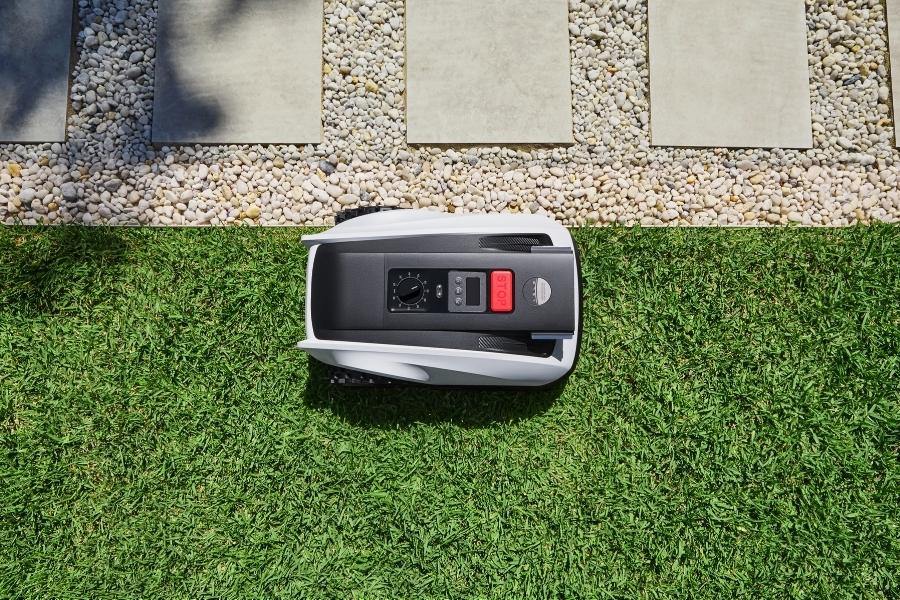 robot tondeuse goat longeant la bordure entre pelouse et allee en gravier