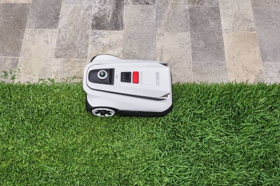 top view of a goat robot lawn mower trimming the edge between grass and tile