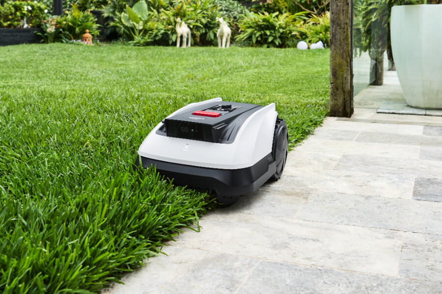 goat robot lawn mower mowing the edge of a playground