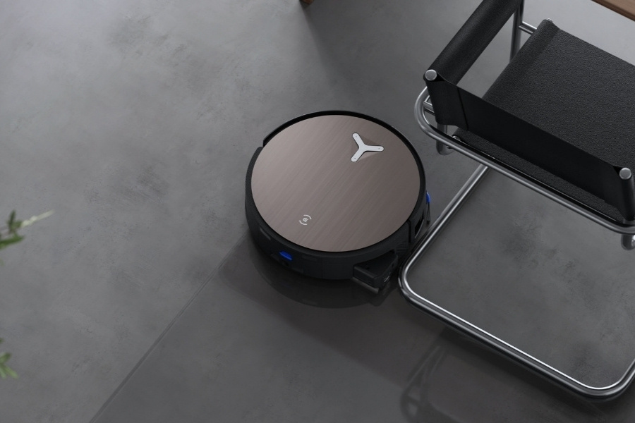 deebot robot vacuum cleaning concrete floor near dinner chair
