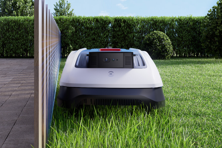 goat robot mower mowing next to a fence