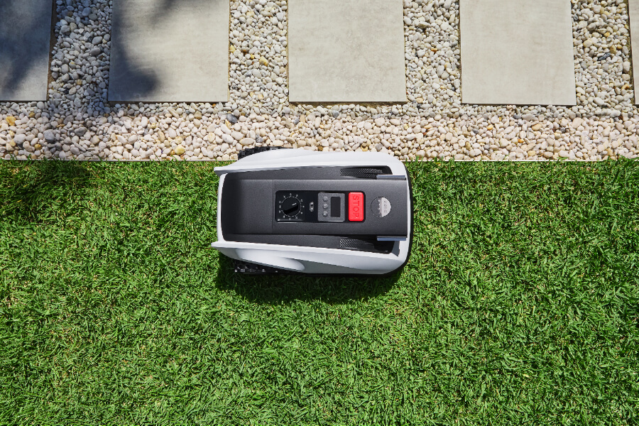 goat robot mower mowing along the edge of a sand pit