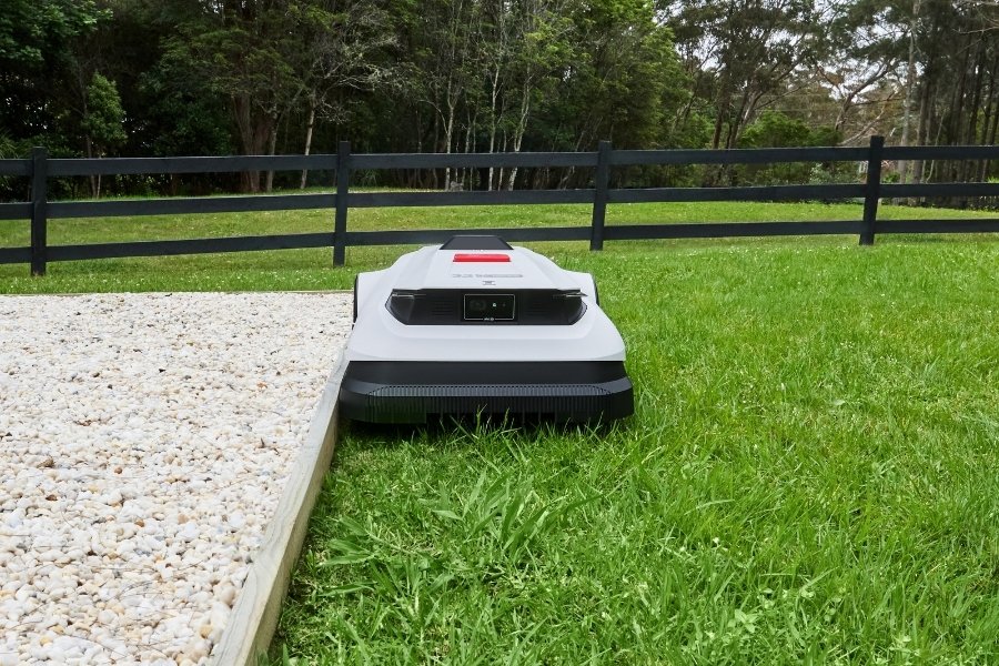 goat robot lawn mower mowing the edge of a playground