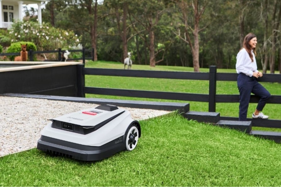 goat robot mowers mowing large garden in front of a couple