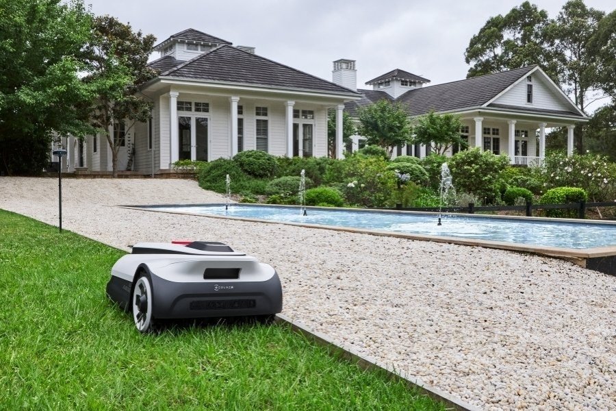 goat robot lawn mower mowing next to a pool in a large garden