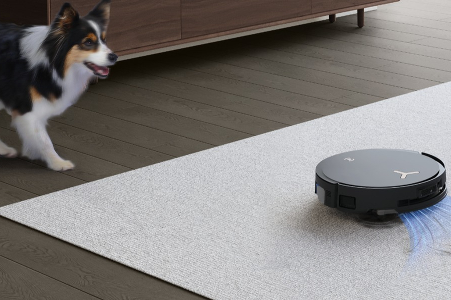 dog standing next to robot vacuum cleaner