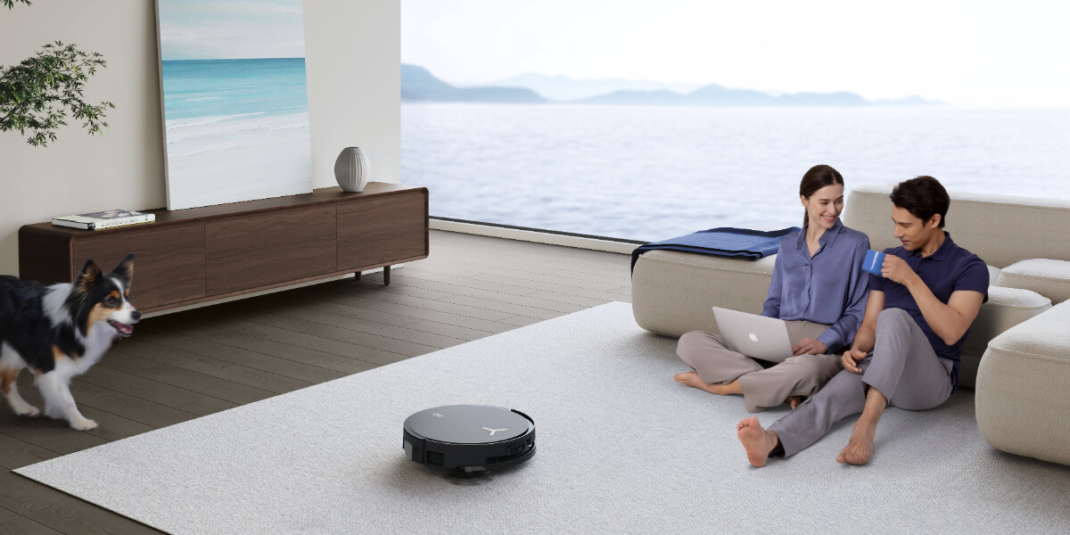 the robotic vacuum cleans alongside a couple enjoying their leisure time