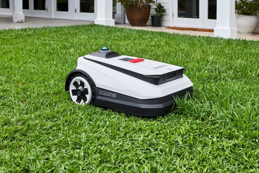 goat robot mower cutting tall grass in the backyard