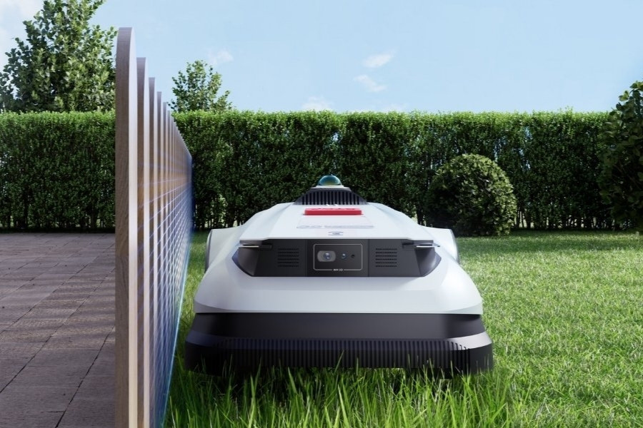 goat robot mower mowing next to a fence
