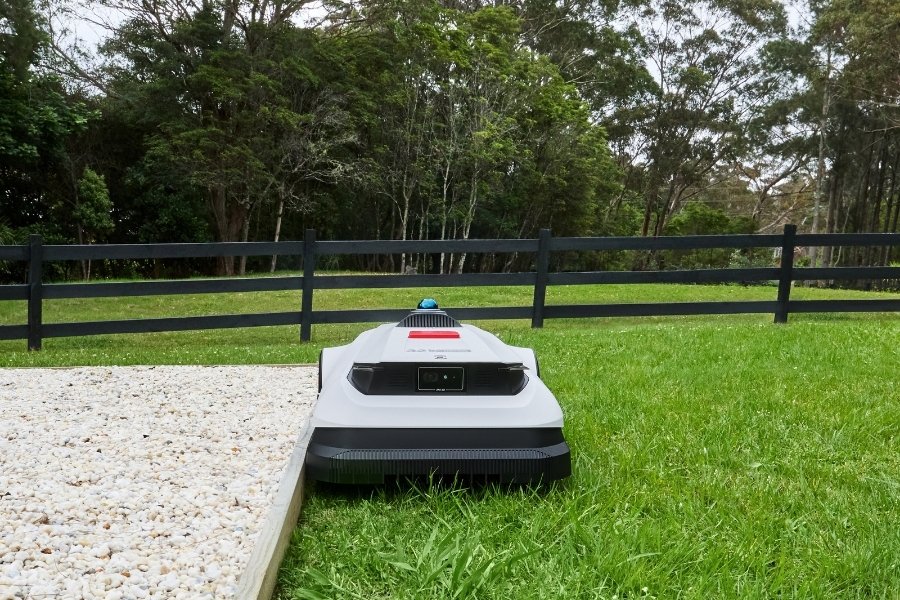 goat robot mower mowing along the edge of a sand pit