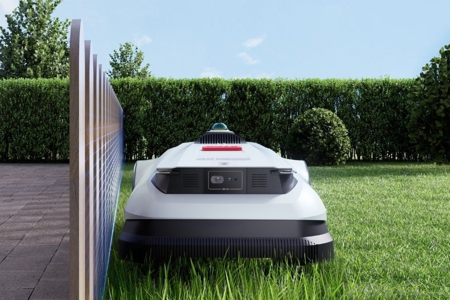 tondeuse robot chèvre tondant à côté d’une clôture